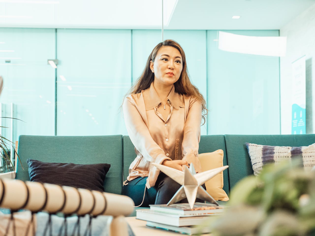 services-01 Professional woman sitting on a sofa in a contemporary office setting, conveying calm and focus.